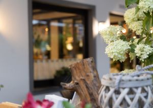 Weiße Hortensienblüten und eine rustikale Holzdeko mit Laterne vor dem Fenster des Restaurants.