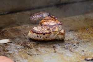 Dicke Fleischmedaillons braten direkt auf einer heißen Grillplatte.