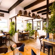 Schöner Restaurantinnenraum mit Holztischen und grünen Zimmerpflanzen