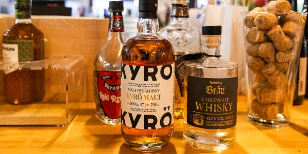 Flaschen von Kyrö Malt Rye Whisky und Fürstenberg Bräu Single Malt Whisky auf einem Tresen neben einem mit Korken gefüllten Glas.