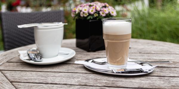 Latte Macchiato mit luftigem Milchschaum und Blick auf Blumen