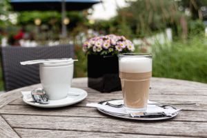 Latte Macchiato mit luftigem Milchschaum und Blick auf Blumen